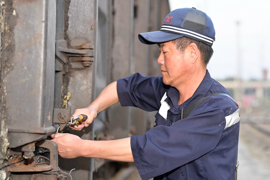 哈南站貨檢車間下行五場貨運檢查員正在對車輛中門進行捆綁加固。
