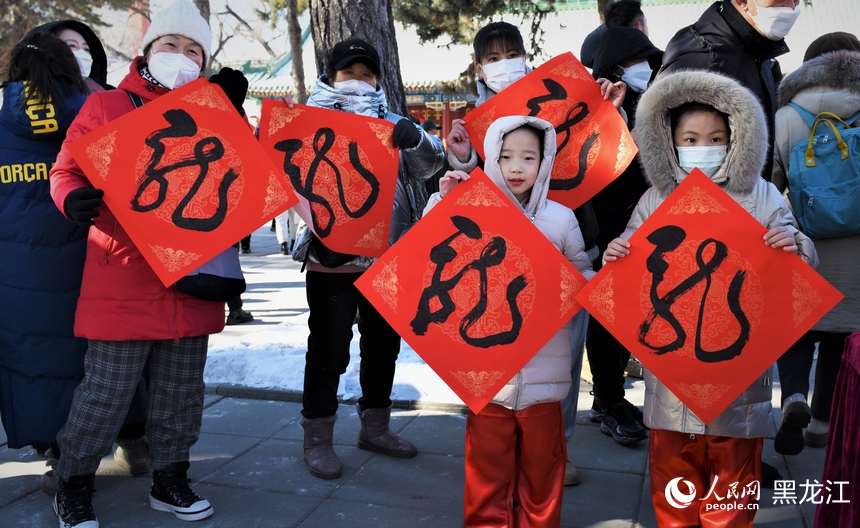 書法家揮毫潑墨書寫“龍”字，市民領取后進行展示。人民網 蘇靖剛攝